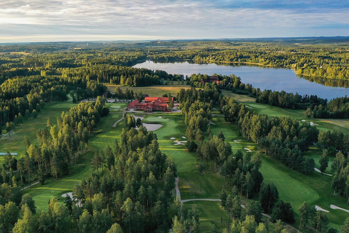 Aerial view of a lakeside Finnish golf course and clubhouse in evening light